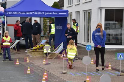 Kinder mit gelben sewikom-Warnwesten nehmen an einem spielerischen Baustellen-Parcours teil. 